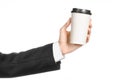 Business lunches coffee theme: businessman in a black suit holding a white blank paper cup of coffee with a brown plastic cap isol Royalty Free Stock Photo