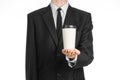 Business lunches coffee theme: businessman in a black suit holding a white blank paper cup of coffee with a brown plastic cap isol Royalty Free Stock Photo