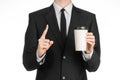 Business lunches coffee theme: businessman in a black suit holding a white blank paper cup of coffee with a brown plastic cap isol Royalty Free Stock Photo