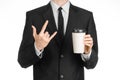 Business lunches coffee theme: businessman in a black suit holding a white blank paper cup of coffee with a brown plastic cap isol Royalty Free Stock Photo