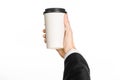 Business lunches coffee theme: businessman in a black suit holding a white blank paper cup of coffee with a brown plastic cap isol Royalty Free Stock Photo