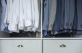 Business male wardrobe hanging white shirts blazer coat clothing on hangers dresser drawer closeup