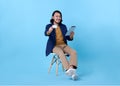 Business man asian happy smiling showing credit card and using a digital tablet while sitting on chair isolated on bright blue Royalty Free Stock Photo