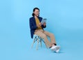 Business man asian happy smiling using a digital tablet while sitting on chair isolated on bright blue background