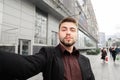 Business man with beard standing against the background of the street and take selfie Royalty Free Stock Photo