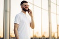 Business man with a beard in sunglasses talking on a cell phone in the city. A man holds a smartphone close to his ear Royalty Free Stock Photo