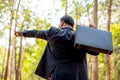 Business man with black suit and briefcase look to the forest and also point to some directions to think about plan of land or Royalty Free Stock Photo