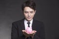 Business man in black suit and holding pink piggy bank