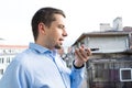 Business man with blue shirt using voice recognition in smart phone in the balcony