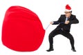 Business man carrying a heavy gift sack with christmas hat