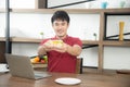 The business man with casual  red t-shirt having breakfast and eating sandwich, drinking coffee. Young man working on labtop Royalty Free Stock Photo