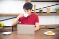 The business man with casual  red t-shirt messaging on mobile phone, drinking coffee and eating sandwich, Young man working on Royalty Free Stock Photo