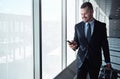 Business man, cellphone and window in airport hallway for reading, thinking or vision on international travel Royalty Free Stock Photo