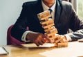 Business man challenge pulling block wood building tower, the block wood has failling on he hand