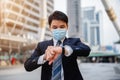 Business man checking time on his watch and wearing medical mask during coronavirus covid-19 pandemic in city Royalty Free Stock Photo