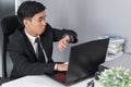 Business man checking time on watch while using laptop Royalty Free Stock Photo