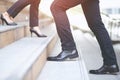 Business man close-up legs walking up and working woman go down the stair in city. walk by in opposite directions in rush hour to