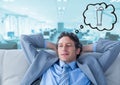 Business man on couch dreaming of cocktail against blurry blue office Royalty Free Stock Photo