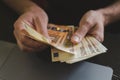 business man counting money. rich male hands holds and count cash banknotes of 50 euros bills or notes currency in front of a lapt Royalty Free Stock Photo