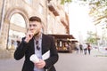 Business man with documents in his hands eats a snack while walking to work Royalty Free Stock Photo