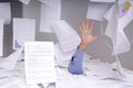 Business man drowning in a desk full of papers