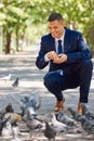 Business, man and feeding birds outdoor in the park during a work break for happiness and peace. Businessman, feed and