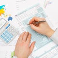 Business man filling out 1040 US Tax Form with calculator next to this left hand - close up studio shot Royalty Free Stock Photo