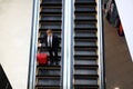 Business man going down escalator holding travel bag. Royalty Free Stock Photo