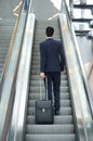 Business man going up escalator with bag Royalty Free Stock Photo