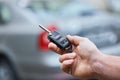 Business man hand holding car keys front with car on background. parking in front of the house. transportation concept.