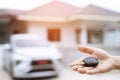 Business man hand holding car keys front with new car on background. parking in front of the house. transportation concept. Royalty Free Stock Photo