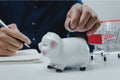 Business man hand holding coin money saving at piggy bank.Business economy management finance investment market and shopping