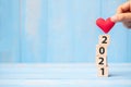 Business man hand holding red heart shape over 2021 wooden cubes on blue table background with copy space for text. Business, Royalty Free Stock Photo