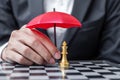 Business man hand holding red Umbrella cover Chess King figure. Business, Risk Management, Solution, economic regression,