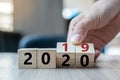 Business man hand holding wooden cube with flip over block 2019 to 2020 word on table background. Resolution, strategy, solution, Royalty Free Stock Photo