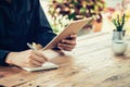 Business man hand writing note pad and holding tablet in coffee Royalty Free Stock Photo