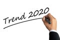 Business man hand writing word trend 2020 with black color marker pen isolated on white background.TRENDS 2020 Business Concept. Royalty Free Stock Photo