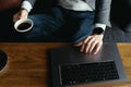 Business man hands working on laptop holding cup of coffee