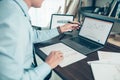 Business man hold stylus pen and pointing to laptop at office  with document report, graph, financial report on screen Royalty Free Stock Photo