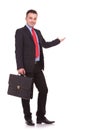 Business man holding a black brief case while presenting Royalty Free Stock Photo