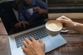 Business man holding coffee cup and typing on laptop computer keyboard on wooden table. Close up male hands with notebook pc Royalty Free Stock Photo