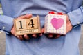 Business man holding 14 February wooden calendar and heart gift box. Valentine day concept