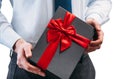 Business man holding a gift with a red ribbon. Guy on a white background in a light shirt with a tie. Black gift box Royalty Free Stock Photo