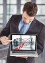 Business man holding laptop showing red arrow with black business doodles against blurry background Royalty Free Stock Photo