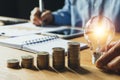 Business man holding light bulb on the desk in office and writing on note book it for financial,accounting,energy,idea concept. Royalty Free Stock Photo