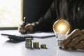 Business man holding light bulb on the desk in office and writing on note book it for financial,accounting,energy,idea concept Royalty Free Stock Photo