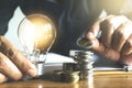 Business man holding light bulb and a coin on the desk in office for financial,accounting,energy,idea concept.