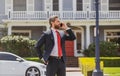 Business man holding mobile cell phone using app texting sms message wearing suit. Young urban professional man using Royalty Free Stock Photo
