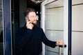 Business man holding the office door and get outdoor white speak on phone. Man get out exit from office building Royalty Free Stock Photo