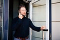 Business man holding the office door and get outdoor white speak on phone. Man get out exit from office building Royalty Free Stock Photo